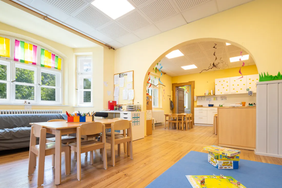 Gro&szlig;er, bunter Gruppenraum vom Kindergarten mit Brettspielen, Tischen und St&uuml;hlen mit Stiften zum Malen