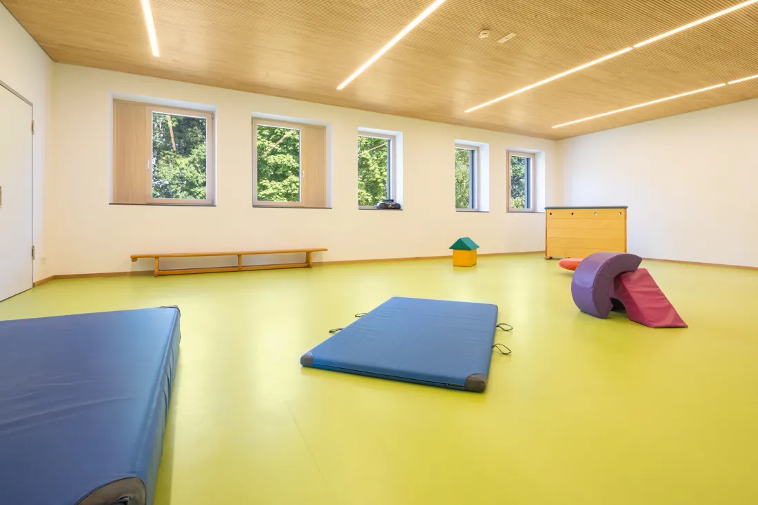 Turnhalle mit gr&uuml;nem Boden, Matten und Schaumstoffspielzeug zum Spiel und Sport